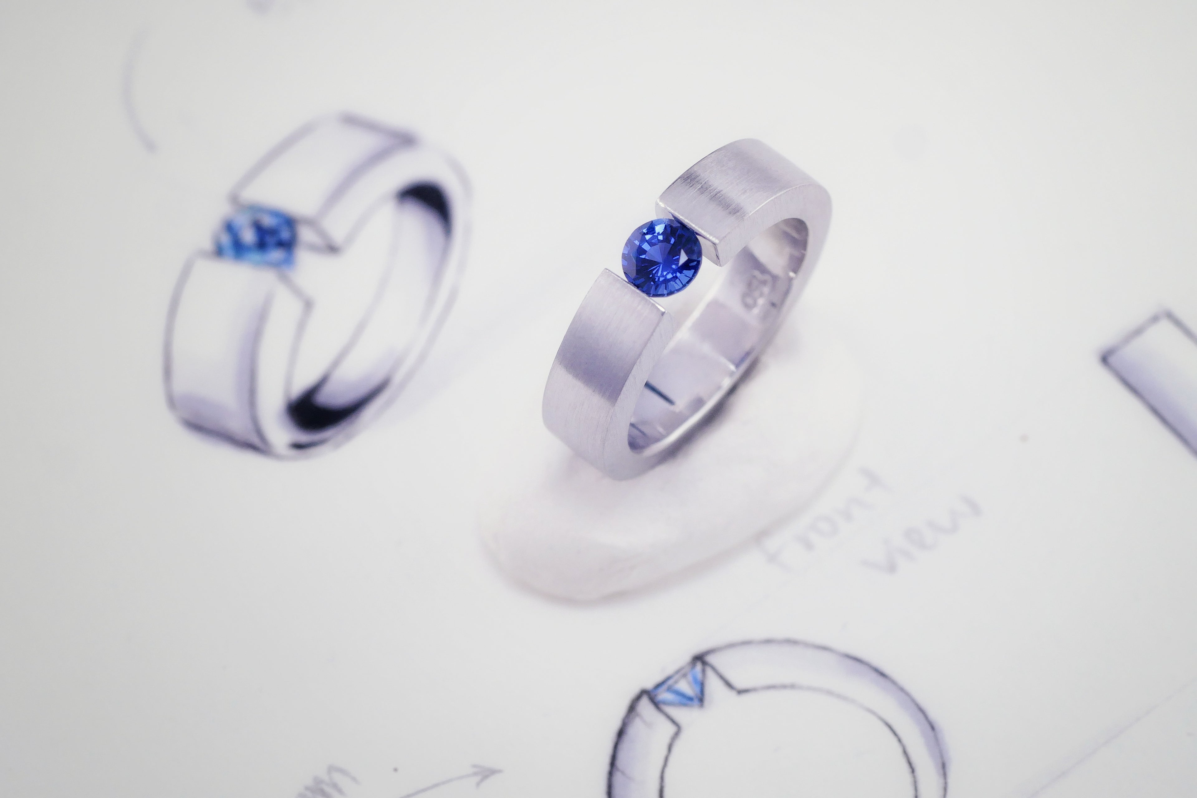 18K white gold tension ring with a suspended blue sapphire