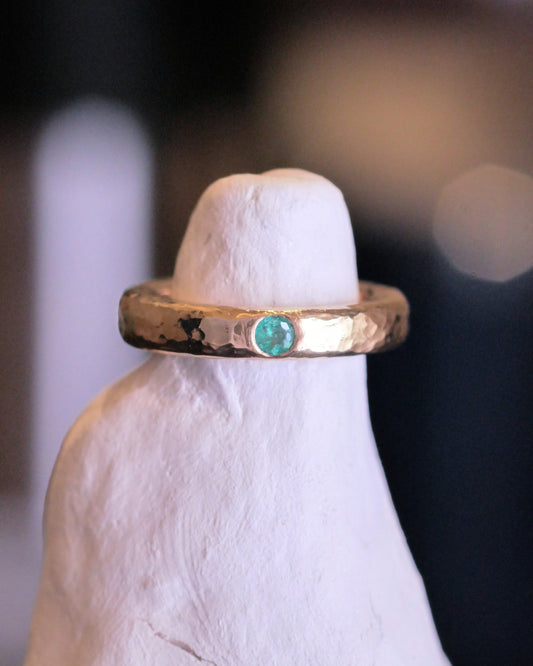 18k yellow gold ring with a thick hammer textured band and an emerald gemstone